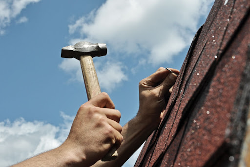 A roofer places a roofing nail.